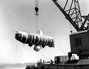 The bathyscaphe Trieste is hoisted from the water during testing before her deep-sea dives.