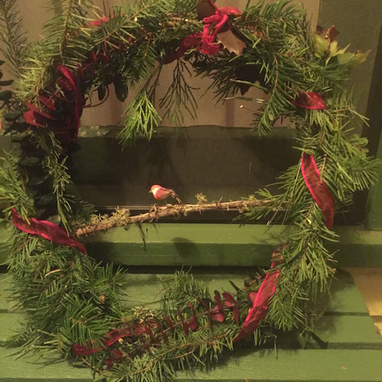 A smaller wreath with a red ribbon and a bird on it. 
