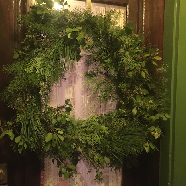 a wreath made of fir, pine, cedar, manzanita, and oregon boxwood, with no bows or anything, hung on a door