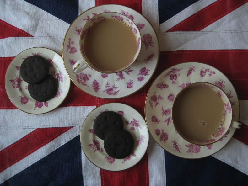 overhead view of teacups and girl scout cookies against a UK flag