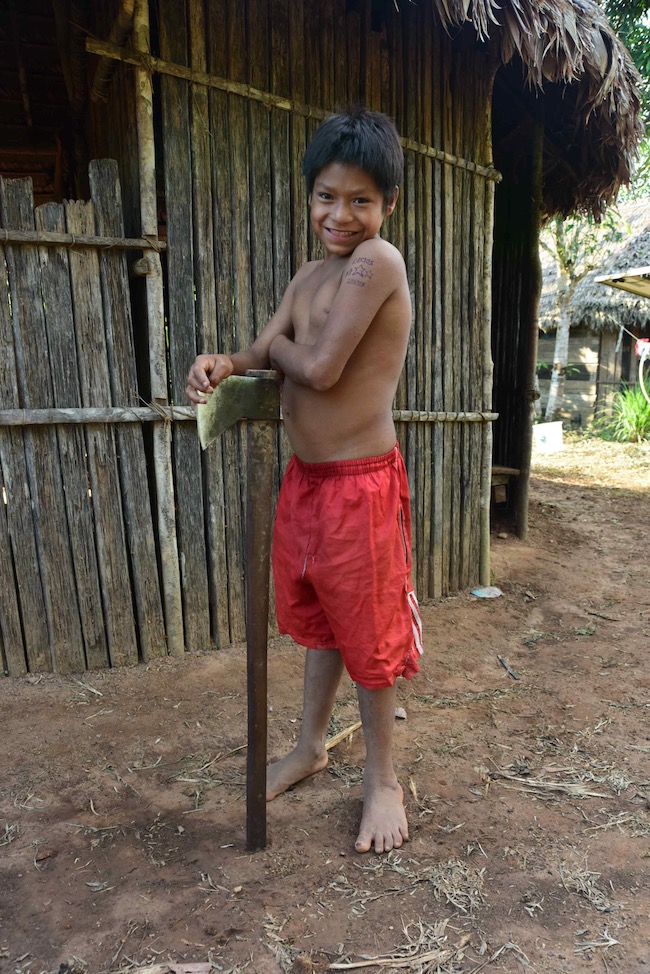 A smiling boy, about age ten, holding an axe nearly as tall as he is.