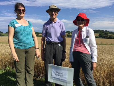 three people stand by a sign that says "stay off the fields"