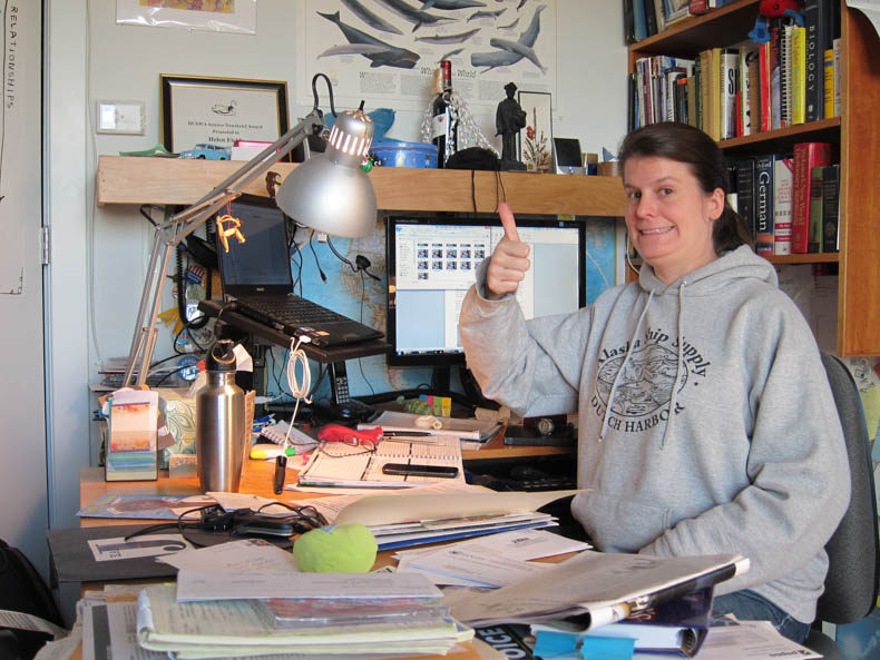 Woman giving thumbs-up in a gray sweatshirt