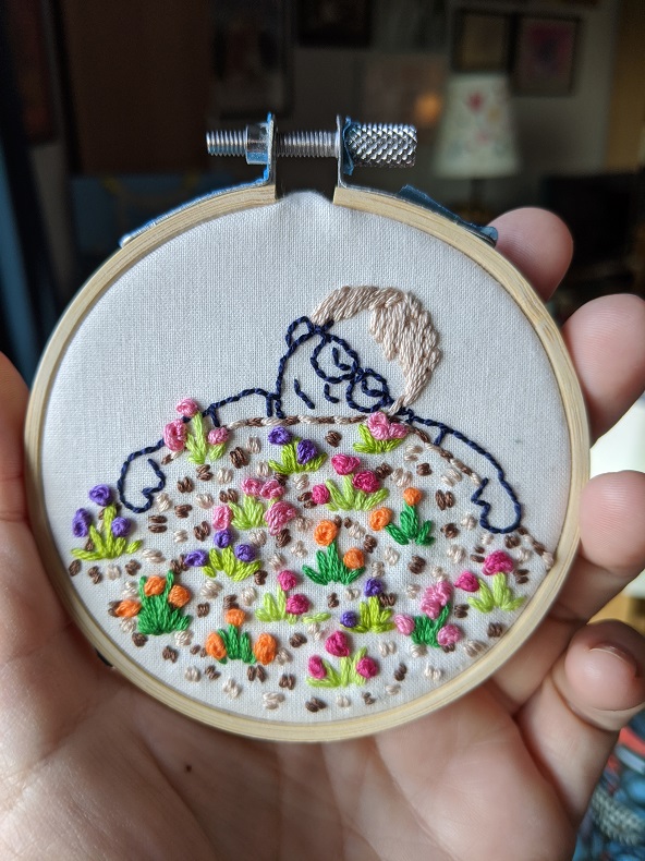 Embroidery of a woman hugging the ground