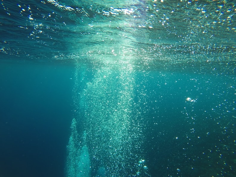 Bubbles at the sea's surface. A trail suggests something has just fallen, or is rising.