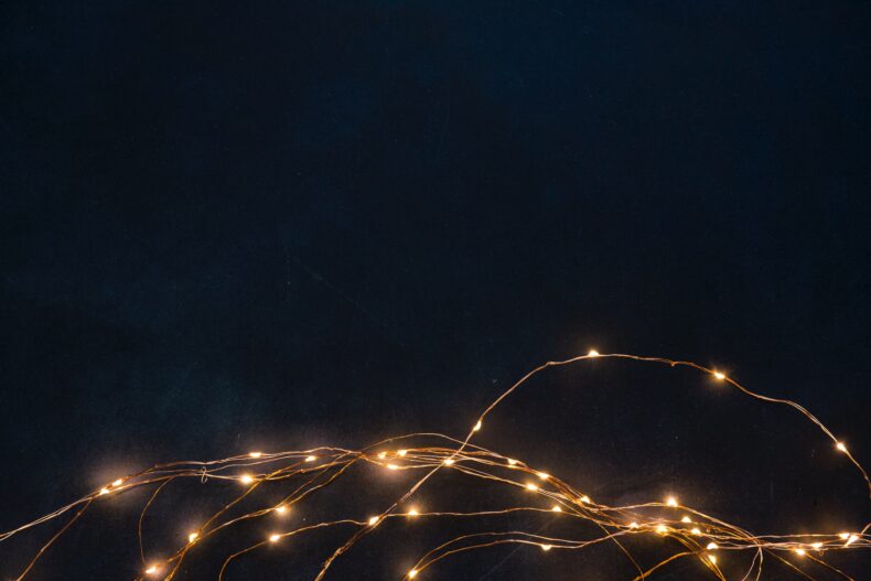 Photograph of a thin, coppery strand of gold fairy lights against a dark background.